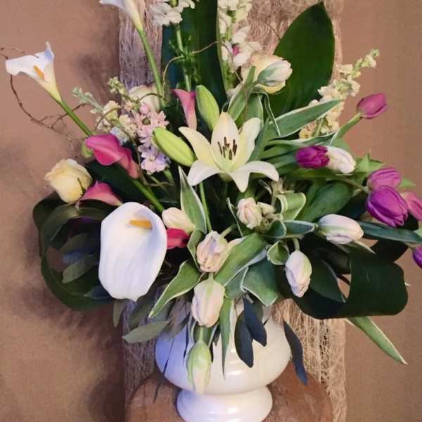 Bouquet of white lilies, calla lilies, and purple tulips in a white vase