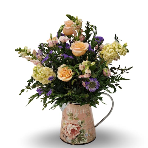 Peach roses and purple flowers arranged in a floral metal pitcher