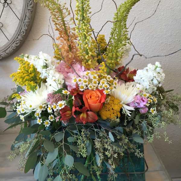 Large mixed flower arrangement in teal glass containers with tall branches