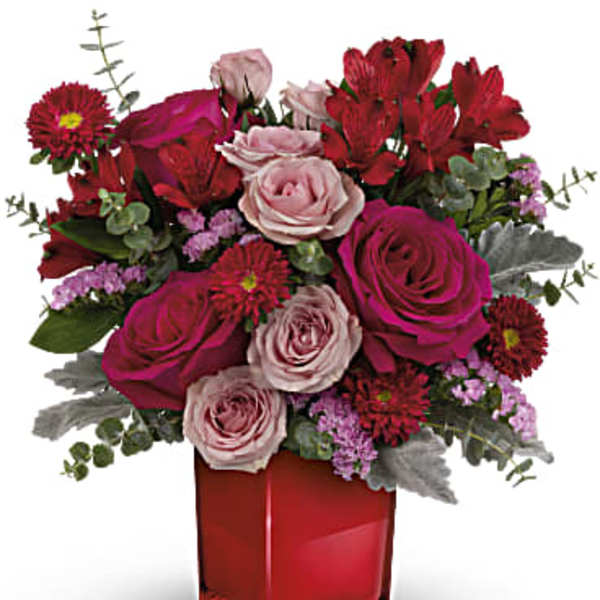 Pink and red rose bouquet in a red glass vase