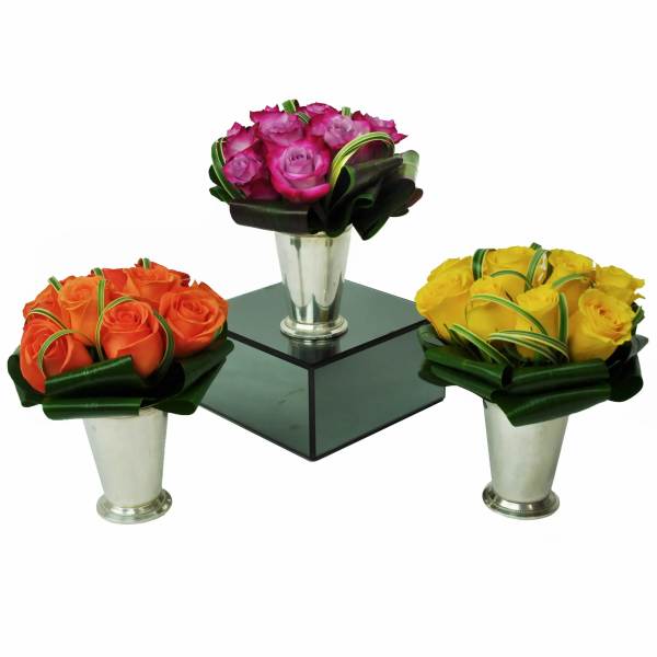 Three rose arrangements in silver vases on a mirrored stand