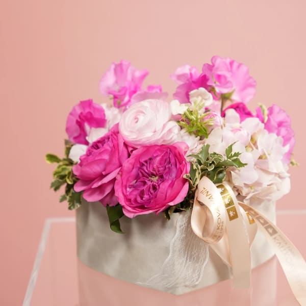 Pink and white flowers arranged in a gray box with a ribbon