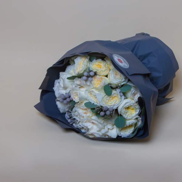 Bouquet of white roses wrapped in dark blue paper