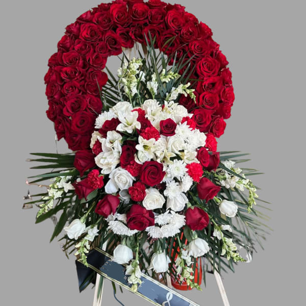 Standing funeral spray of red and white roses with a family ribbon