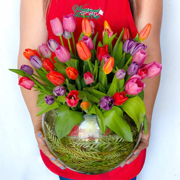 Colorful tulips arranged in a round glass vase