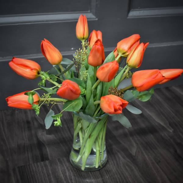 Orange tulips arranged in a clear glass vase