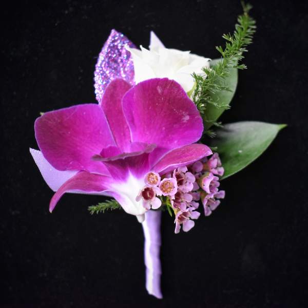 Purple orchid boutonniere with white accent flower and greenery