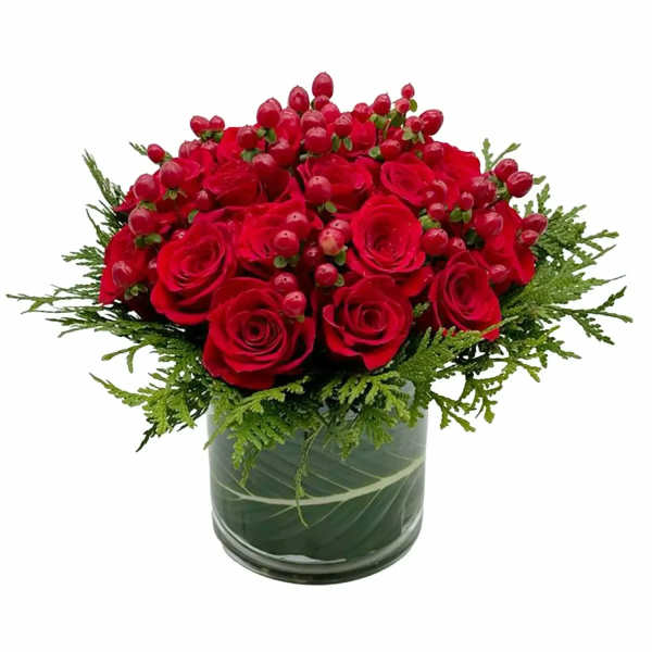 Red roses and berry accents in a glass vase