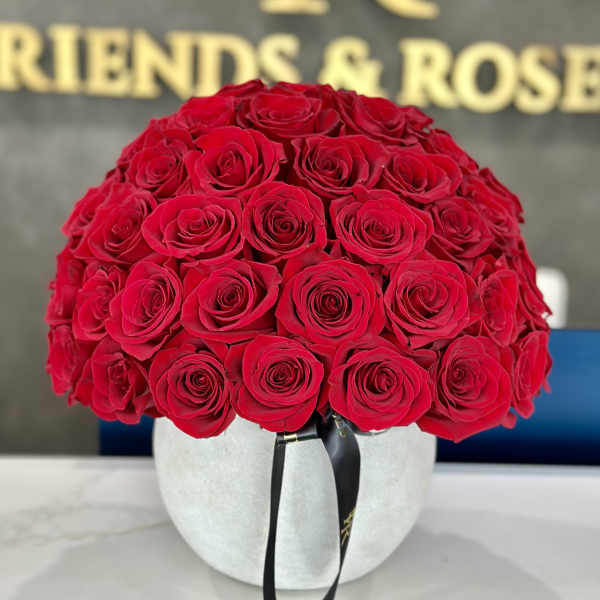 Round bouquet of red roses in a white hat box with a black ribbon