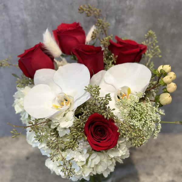 Bouquet of red roses and white orchids in a glass vase