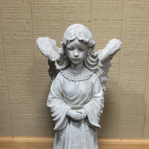 White angel statue with folded hands standing indoors