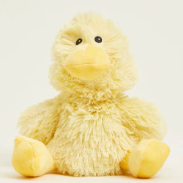 Yellow plush duck with black eyes sitting on a plain background