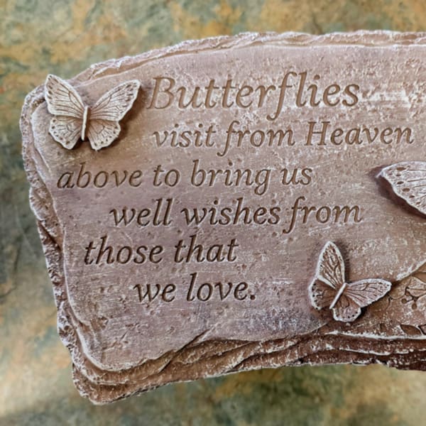 Stone plaque with raised butterflies and a memorial quote engraved on the surface