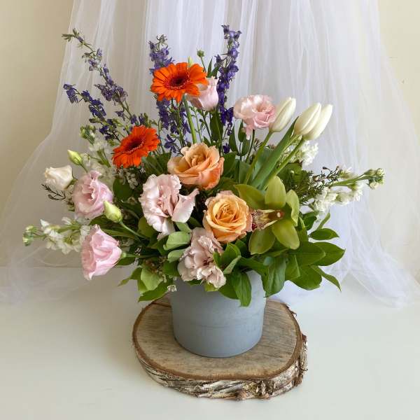 Mixed bouquet in a gray vase with orange, pink, white, and purple blooms