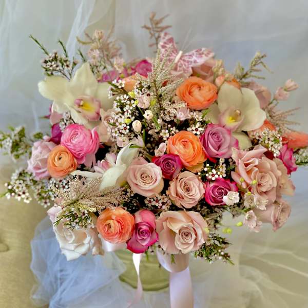 Bouquet of pink, peach, and white flowers with ribbon ties