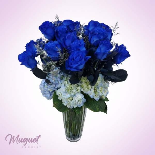 Blue roses and pale hydrangeas in a clear glass vase