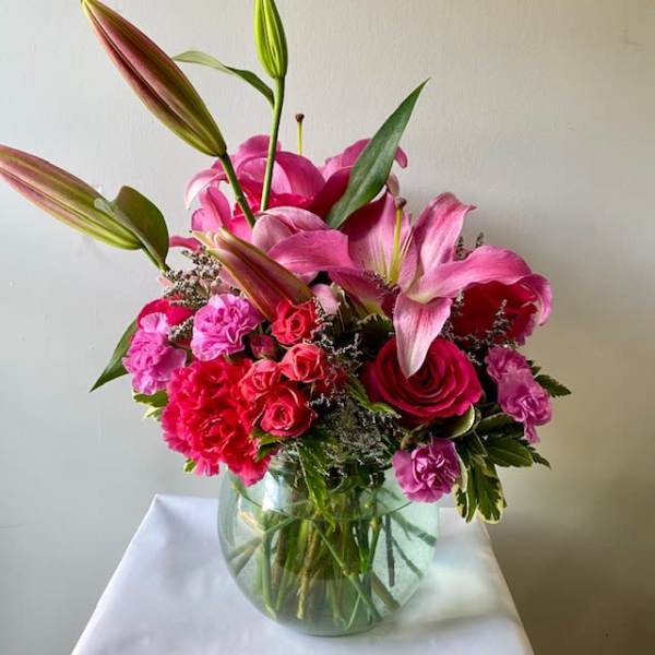 Pink lilies and roses arranged in a clear glass vase