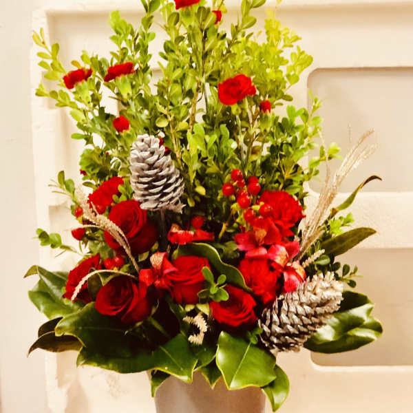 Red rose arrangement in a vase with pinecones and berries