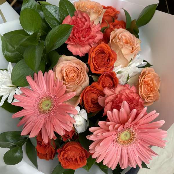 Bouquet of pink gerbera daisies, orange roses, and carnations with white daisies