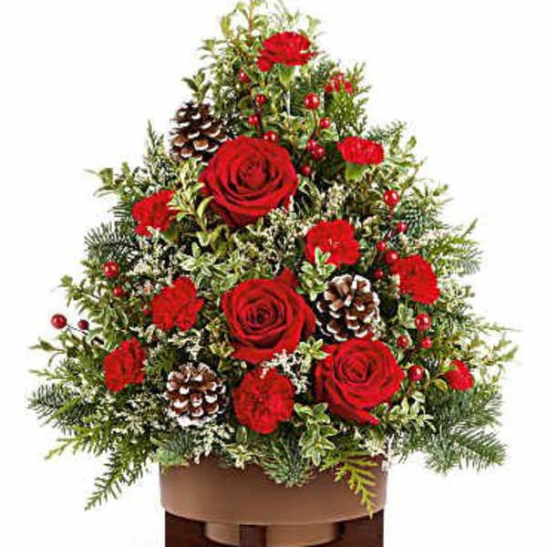 Red roses and carnations arranged in a low wooden container with pinecones
