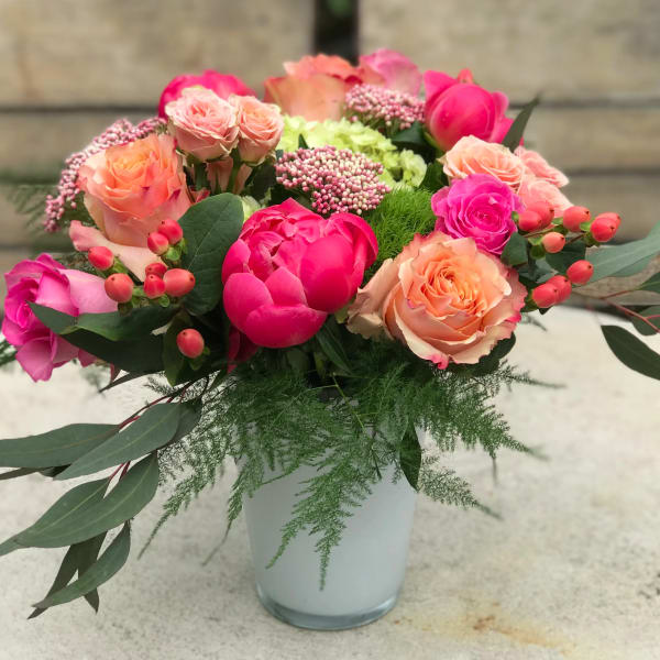 Mixed pink and peach roses in a white vase with greenery