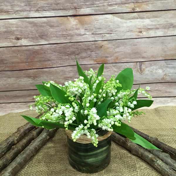 White lily of the valley arrangement in a dark green container
