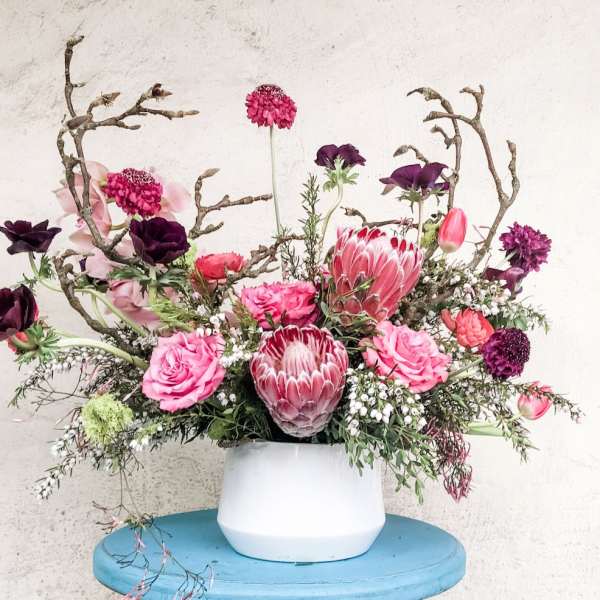 Pink and purple floral arrangement in a white vase