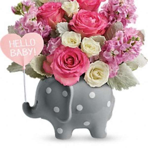 Pink and white roses in a gray elephant planter with a baby balloon