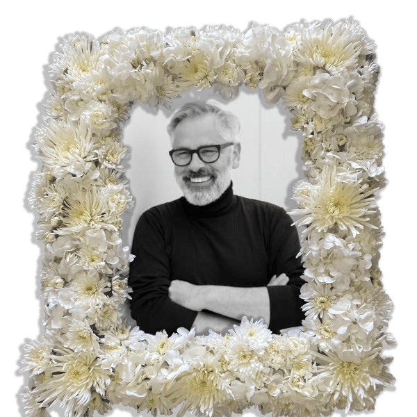 White floral frame surrounding a portrait of a smiling man