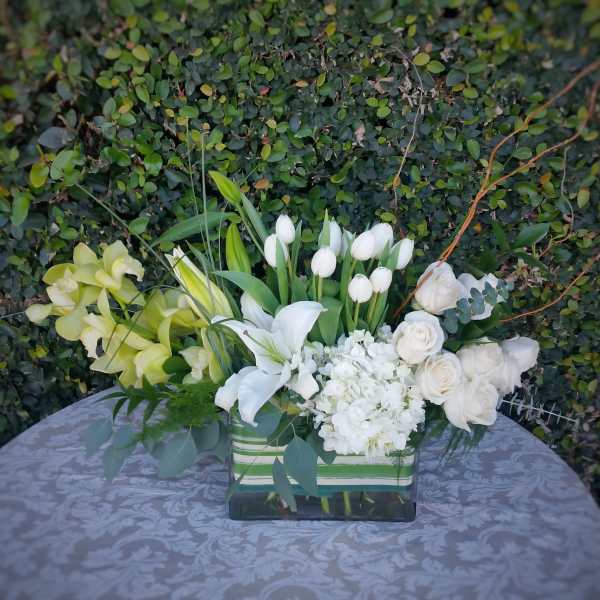 White and pale yellow flowers arranged in a rectangular glass vase