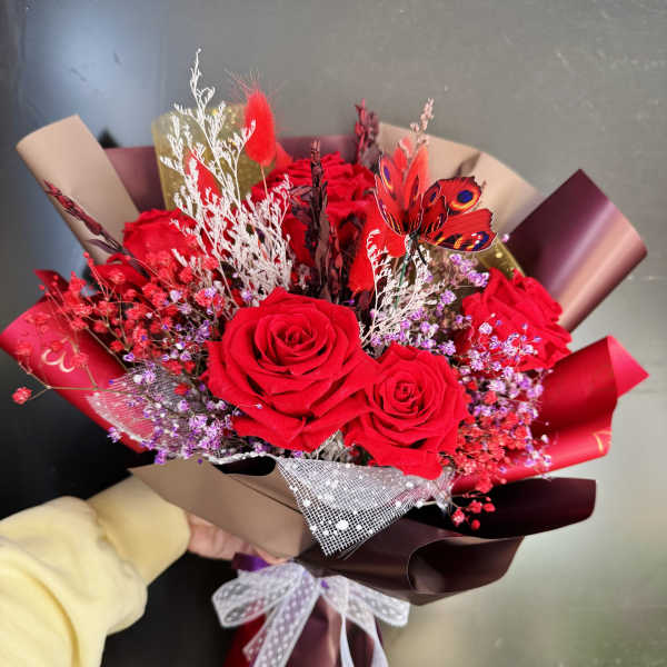 Bouquet of red roses with purple filler and decorative butterfly accents