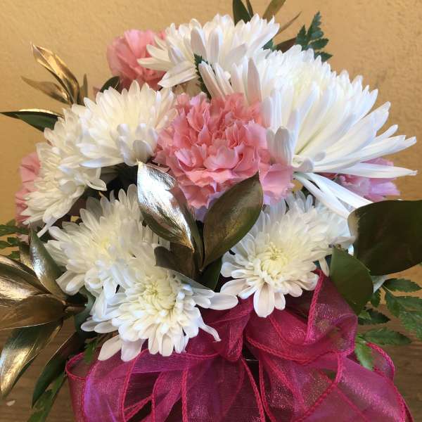 Pink and white chrysanthemum bouquet with a bright ribbon in a vase