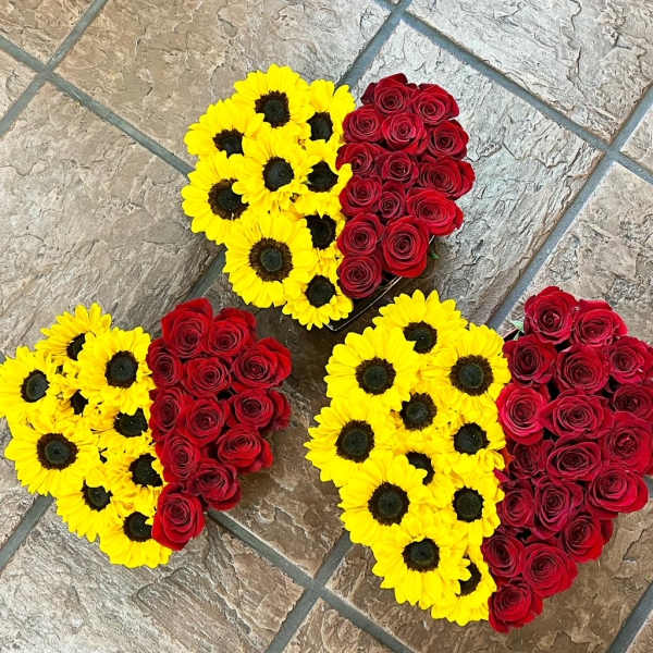 Heart-shaped arrangements of yellow daisies and red roses on tile