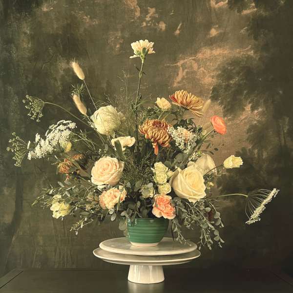 Mixed floral arrangement in a green vase on a pedestal