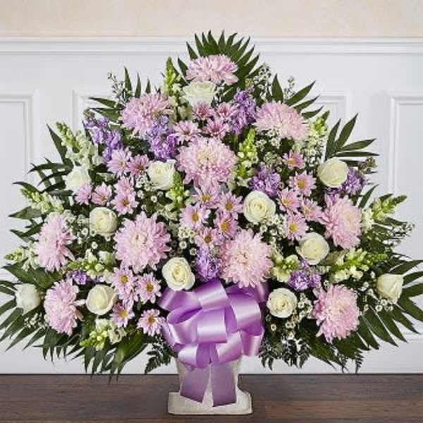 Large pastel floral arrangement with a purple ribbon on a pedestal vase