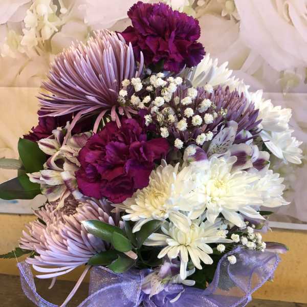 Purple and white bouquet with daisies, carnations, and alstroemeria tied with a lavender ribbon