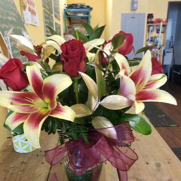 Bouquet of red roses and pink lilies in a glass vase with a ribbon
