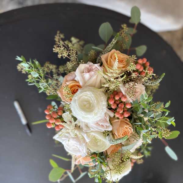 Bouquet of peach and white roses with berries and greenery