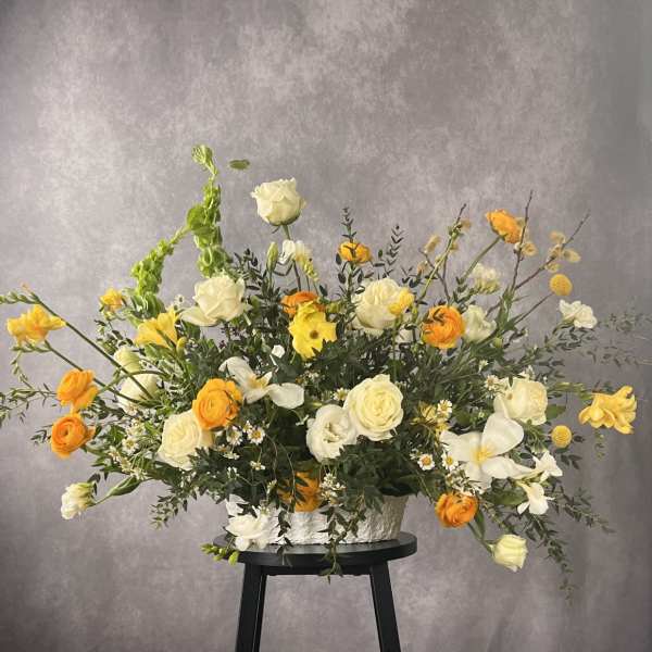 Large yellow and white floral arrangement in a white container