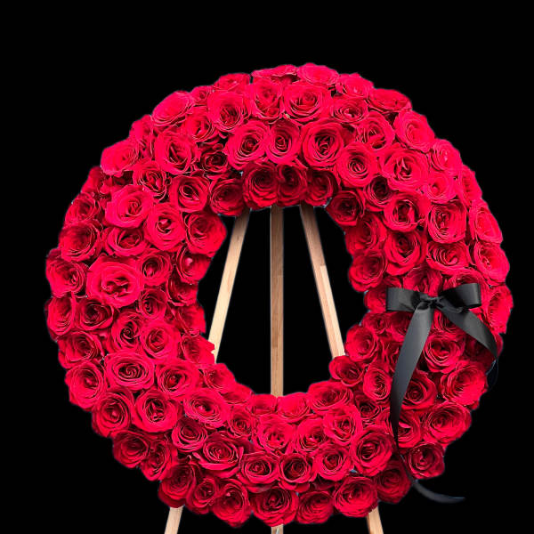 Red rose wreath on a wooden easel with a black ribbon