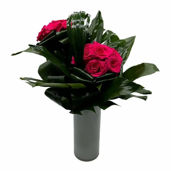 Pink roses arranged with glossy dark leaves in a tall vase