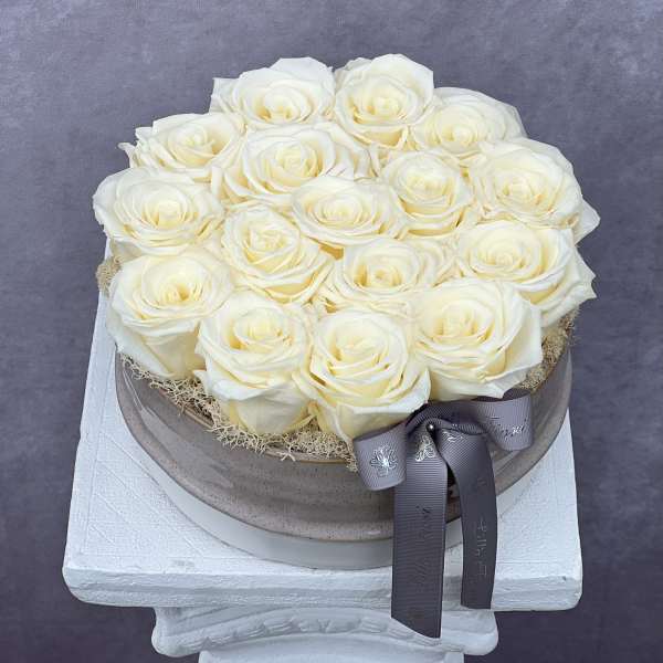 Round box of cream white roses with a gray ribbon bow