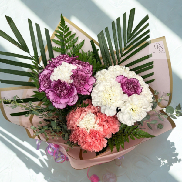 Bouquet of pink, white, and coral carnations with palm fronds