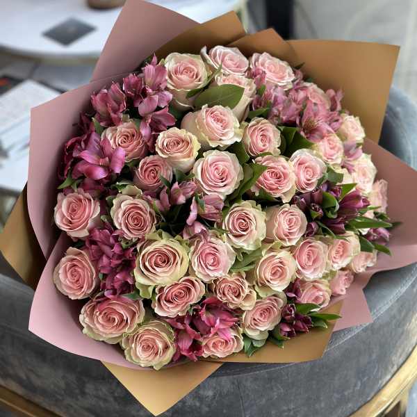 Bouquet of pale pink roses and magenta flowers wrapped in pink and tan paper