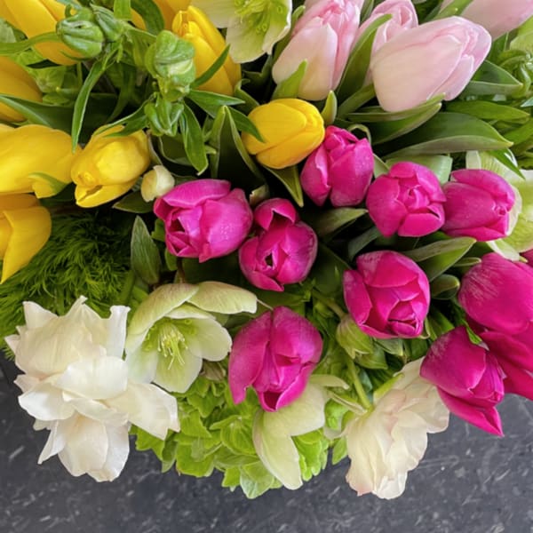 Bouquet of pink, yellow, and white tulips with pale green hellebores