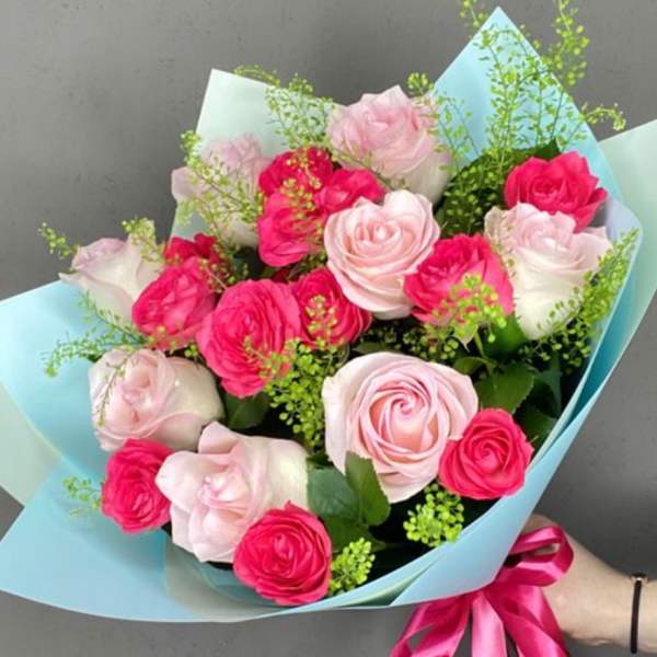 Bouquet of pink and white roses wrapped in light blue paper