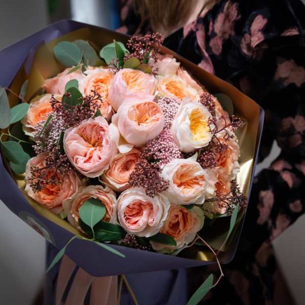 Bouquet of peach and blush roses wrapped in purple paper