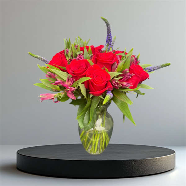 Red roses and pink flowers in a clear glass vase