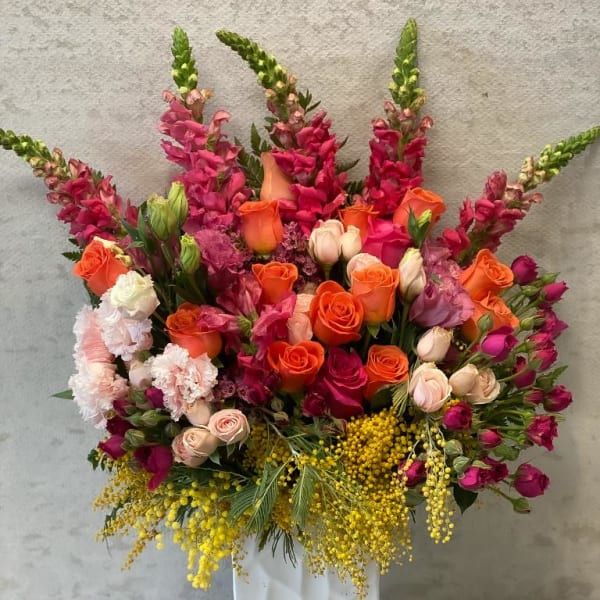 Large mixed bouquet of orange and pink flowers in a white vase