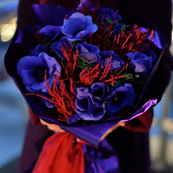 Bouquet of blue flowers wrapped in purple paper with red accents